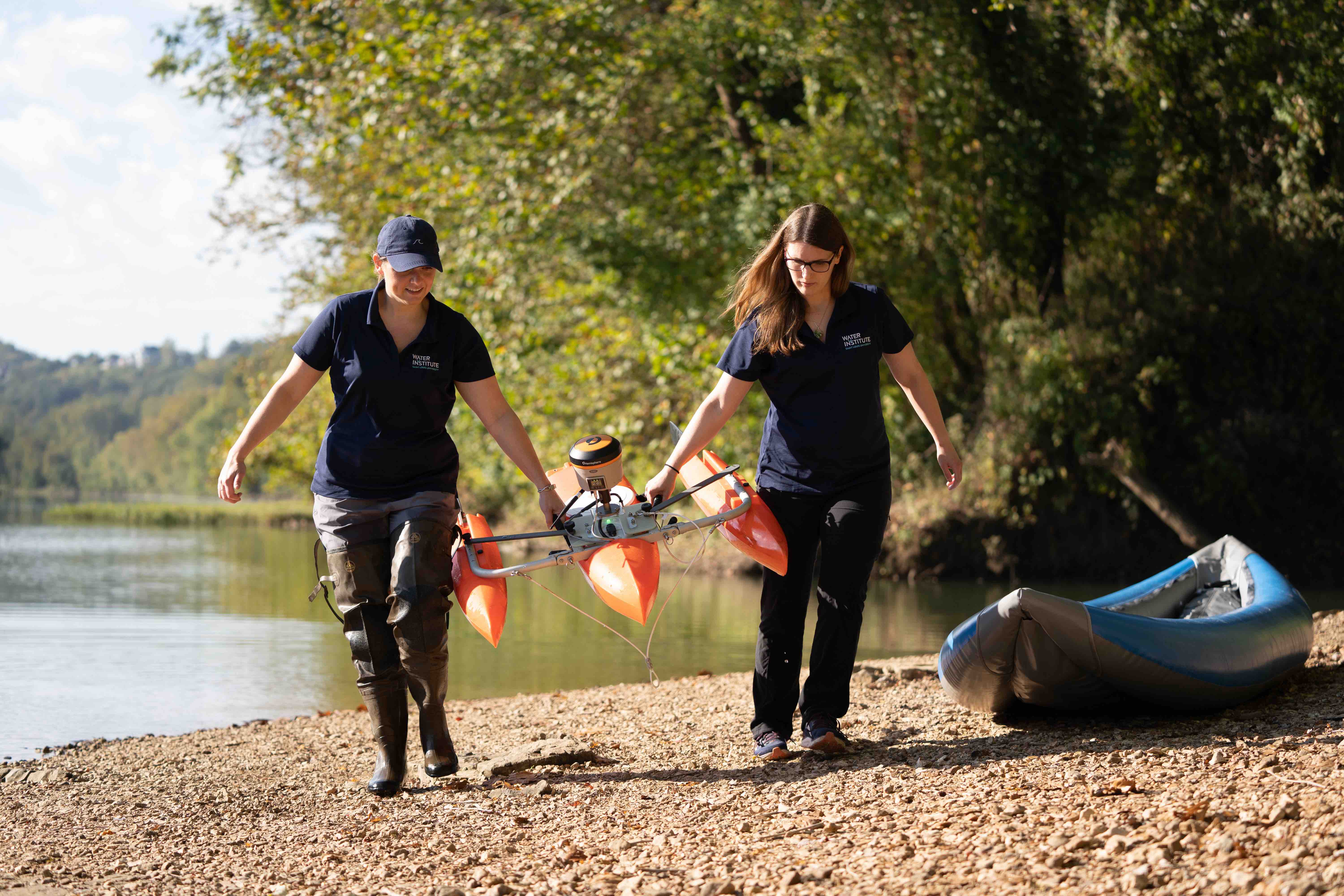 ADCP at Meramec River Dr. Amanda Cox and Dr. Liz Hasenmueller carry the ADCP field instrument attached to an orange catamaran flotation device onto the shore after taking data in Meramec River.